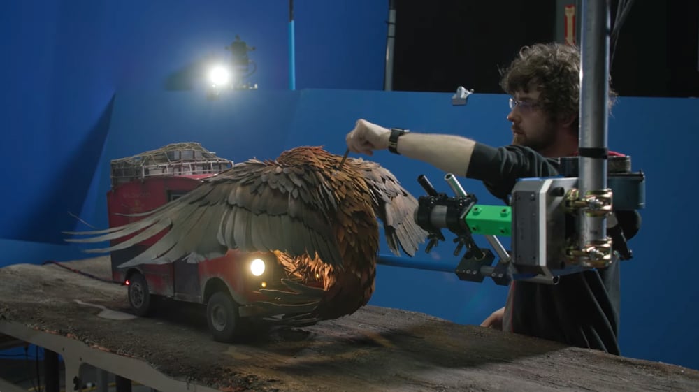 Animator adjusts a large bird puppet on a miniature set during the production of Laika’s stop-motion film Wildwood, highlighting the craft of frame-by-frame animation.